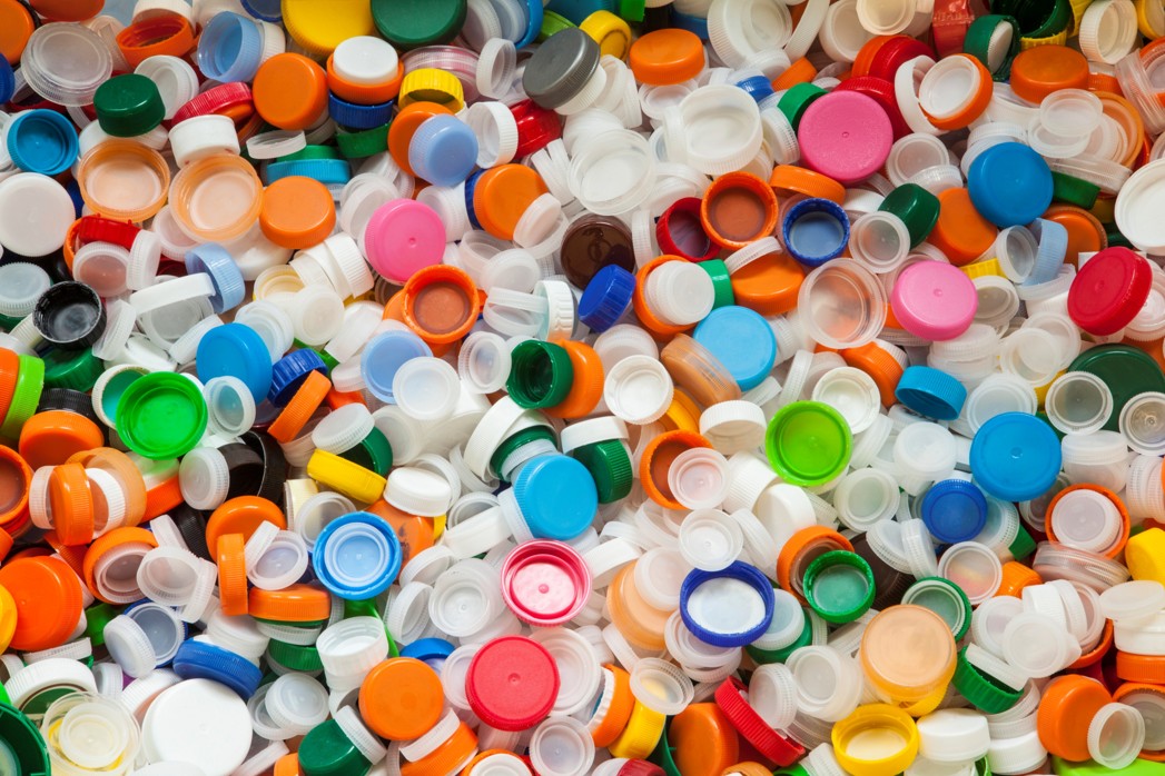 Pile of discarded plastic bottle caps representing a waste management company
